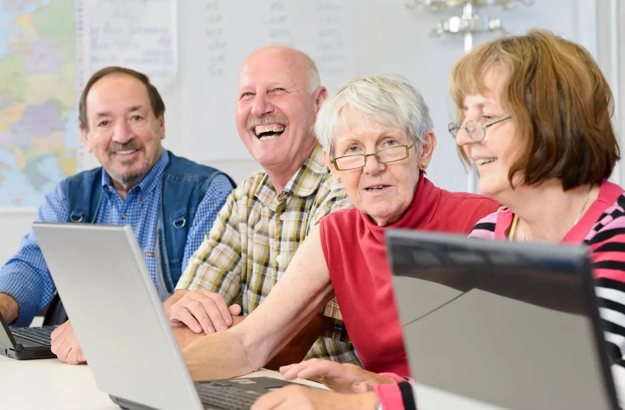 Seniors using laptops and smiling